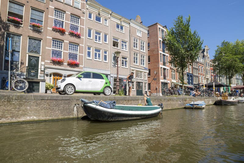 En grabb och en flicka förbereder ett fartyg för att segla på kanalerna av Amsterdam arkivbild En grabb och en flicka förbereder ett fartyg för att segla på kanalerna av Amsterdam arkivbild