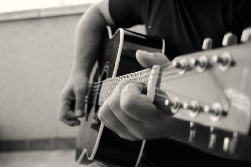 En graktig klockbild av en manlig hand som spelar en akustisk gitarr royaltyfri fotografi