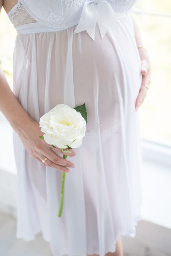 EN GRAVID FLICKA I EN HÄRLIG LÄGRE UNDERKLÄDER ÄR SMOOTING VÅRT DJUR FLICKA MED BLOMMOR PÅ VIT BAKGRUND royaltyfria bilder EN GRAVID FLICKA I EN HÄRLIG LÄGRE UNDERKLÄDER ÄR SMOOTING VÅRT DJUR FLICKA MED BLOMMOR PÅ VIT BAKGRUND royaltyfria bilder