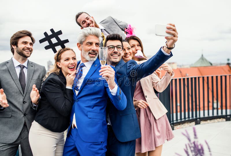 En grupp av glade businesspeople utomhus på takterrass i stad som tar selfie på partiet arkivbild En grupp av glade businesspeople utomhus på takterrass i stad som tar selfie på partiet arkivbild