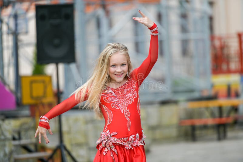 En gullig liten flicka i en röd dräkt dansar på gatan Flicka i dansgruppen Behandla som ett barn flickan lär dans Showdans till fotografering för bildbyråer En gullig liten flicka i en röd dräkt dansar på gatan Flicka i dansgruppen Behandla som ett barn flickan lär dans Showdans till fotografering för bildbyråer