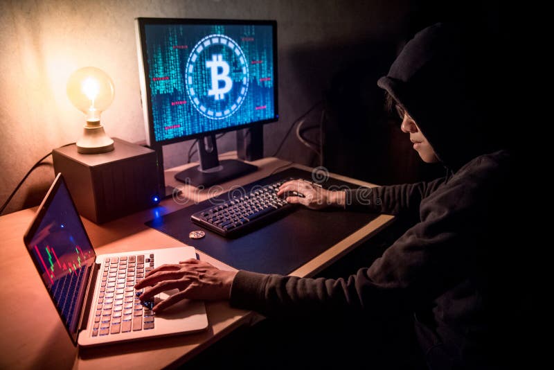 En hackerman som använder datoren för digitalt tvätta för valuta arkivbild