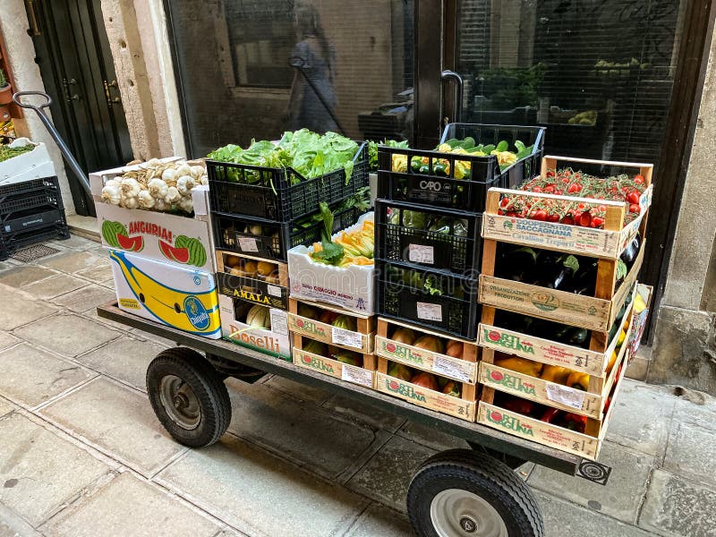 Venice, Italy - September 16, 2023: The hand drawn wagon of a grocer is loaded with crates of fruit and vegetables. A necessary tool for a business in a pedestrian city with no cars or trucks. Venice, Italy - September 16, 2023: The hand drawn wagon of a grocer is loaded with crates of fruit and vegetables. A necessary tool for a business in a pedestrian city with no cars or trucks.