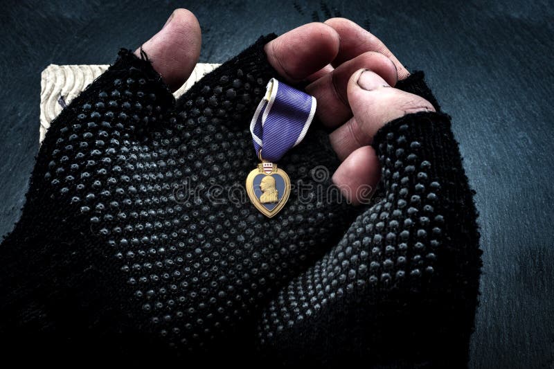 Homeless veterans and social issues concept with grunge image of dirty hands of a homeless man wearing fingerless gloves and holding a purple heart medal. Homeless veterans and social issues concept with grunge image of dirty hands of a homeless man wearing fingerless gloves and holding a purple heart medal