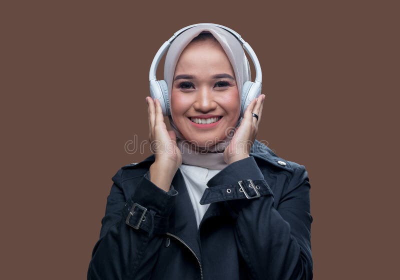 En hijab-kvinna som har på sig trådlösa hörlurar med leende royaltyfri fotografi