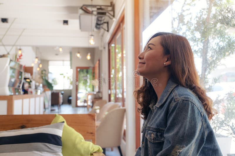 En härlig asiatisk kvinna som sitter i kafé royaltyfri fotografi En härlig asiatisk kvinna som sitter i kafé royaltyfri fotografi