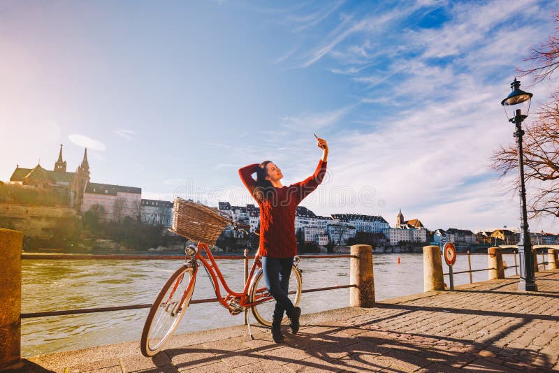 En härlig ung kvinna med en retro röd cykel gör ett foto av henne i den gamla staden av Europa på flodRhenembankmen royaltyfria foton En härlig ung kvinna med en retro röd cykel gör ett foto av henne i den gamla staden av Europa på flodRhenembankmen royaltyfria foton