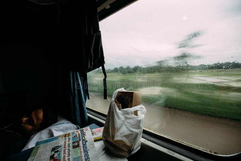 En indisk grabb som sover med mat och tidningen medan ett drev som flyttar sig med gr?n tr?dr?relsesuddighet i yttersidan royaltyfri fotografi En indisk grabb som sover med mat och tidningen medan ett drev som flyttar sig med gr?n tr?dr?relsesuddighet i yttersidan royaltyfri fotografi