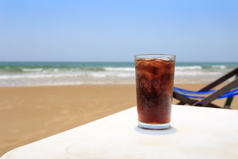 En kall drink i ett exponeringsglas på stranden, arkivbilder En kall drink i ett exponeringsglas på stranden, arkivbilder
