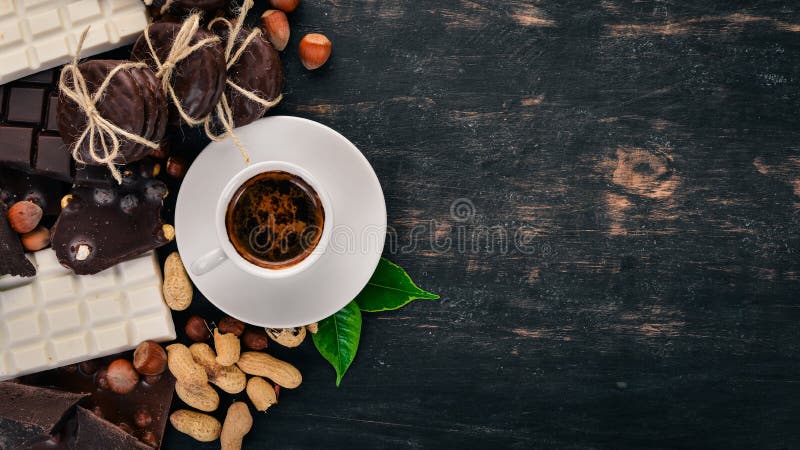 En kopp kaffe och en uppsättning av choklad med kakor och sötsaker På en svart träbakgrund arkivbild En kopp kaffe och en uppsättning av choklad med kakor och sötsaker På en svart träbakgrund arkivbild