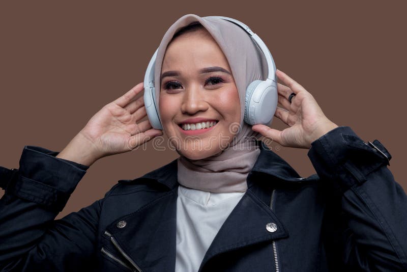 En kvinna i hijab som vill bära trådlösa hörlurar med leende royaltyfri bild