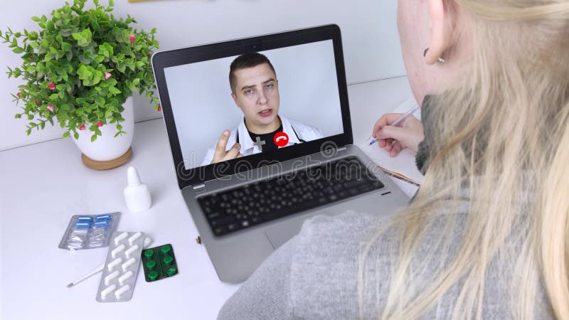 En kvinna kommunicerar via en dator med en läkare via videolänk. Medicinsk assistans under karantänförhållanden. fjärrkonsult