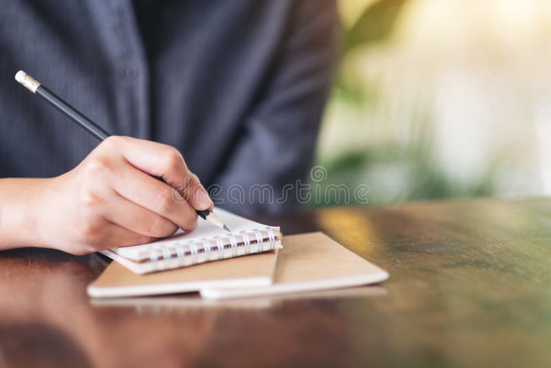 En kvinnas hand som skriver p? den tomma anteckningsboken p? tr?tabellen arkivfoto En kvinnas hand som skriver p? den tomma anteckningsboken p? tr?tabellen arkivfoto