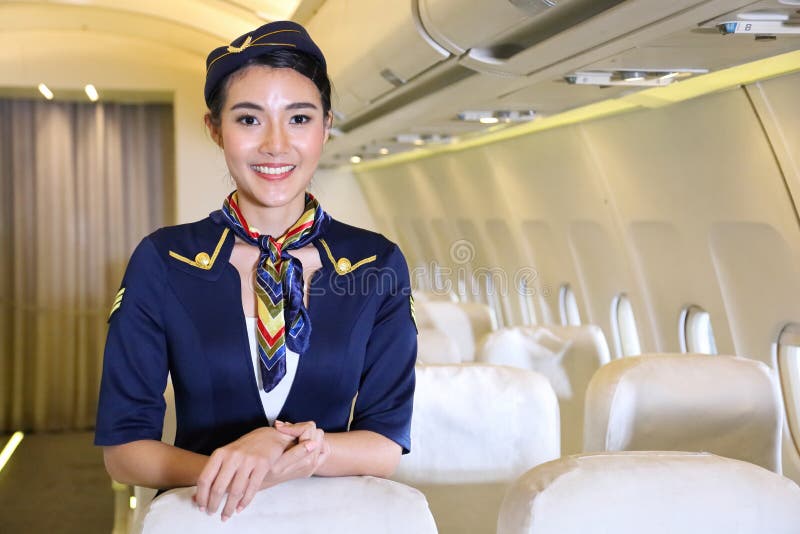 En kvinnlig flygledare som leker inuti flygplanet för att välkomna hela passageraren royaltyfri bild