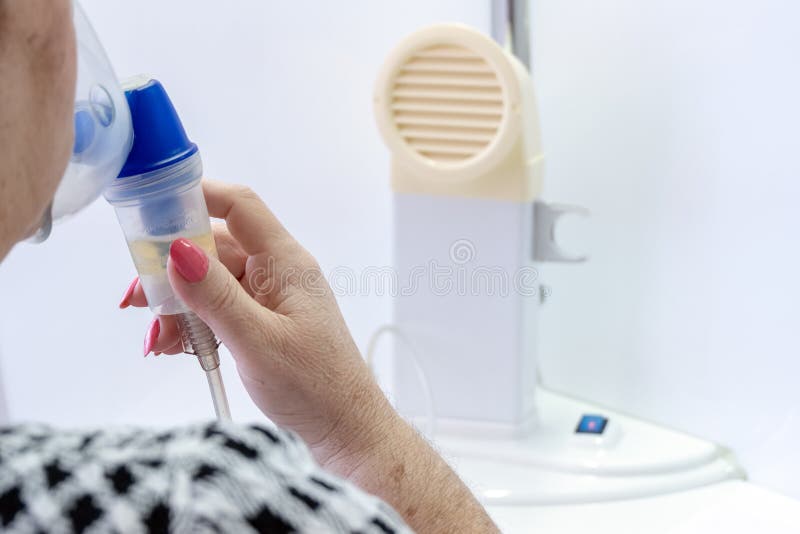 En kvinnlig hand stänger kanterna och näsan med en inhalatormaskering för att andas den medicinska dunsten Inandningtillvägagångs arkivfoto En kvinnlig hand stänger kanterna och näsan med en inhalatormaskering för att andas den medicinska dunsten Inandningtillvägagångs arkivfoto