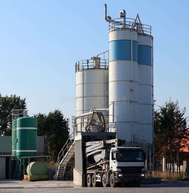 A cement mixer truck is supplied to a concrete silo in a batching plant . A cement mixer truck is supplied to a concrete silo in a batching plant .