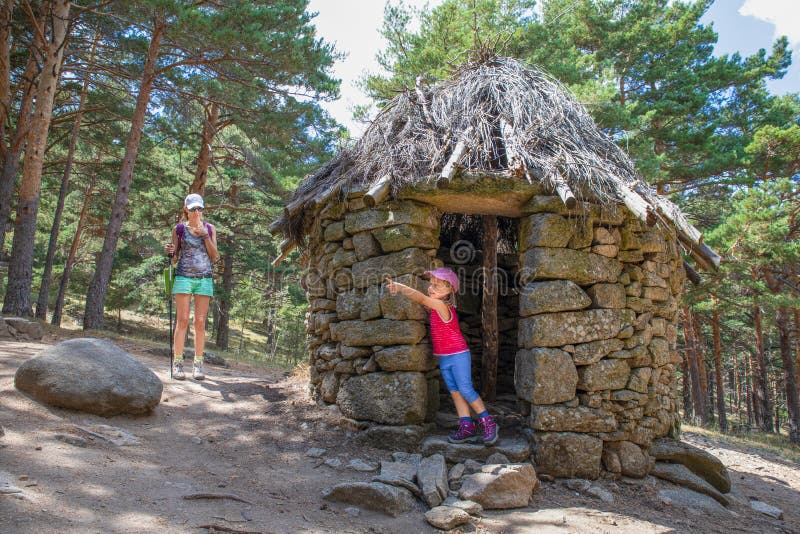 En liten flicka som pekar med fingret i den gamla hut bredvid sin mor i Madrids skog royaltyfria bilder