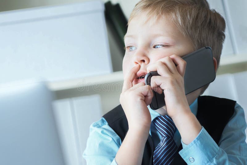 En liten förtroendefull chefschef på kontoret pratar om telefonen som sitter vid skrivbordet med en bärbar dator arkivbilder