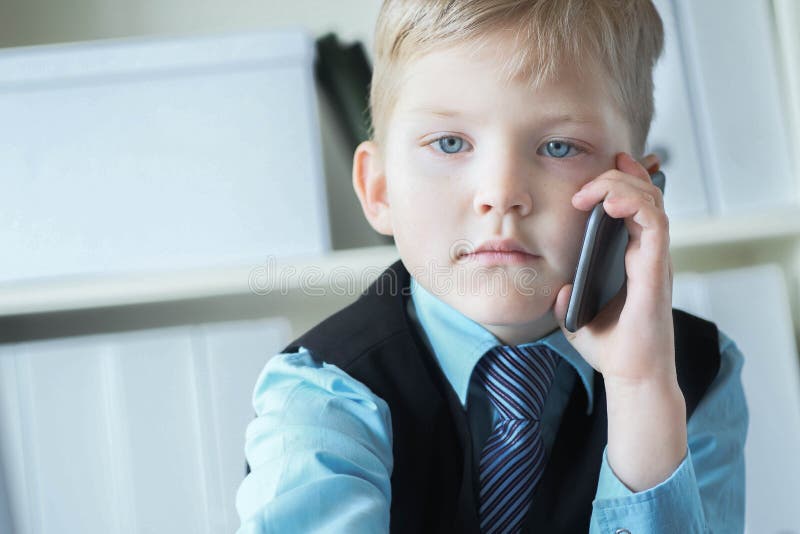 En liten förtroendefull chefschef på kontoret pratar om telefonen som sitter vid skrivbordet med en bärbar dator arkivfoton