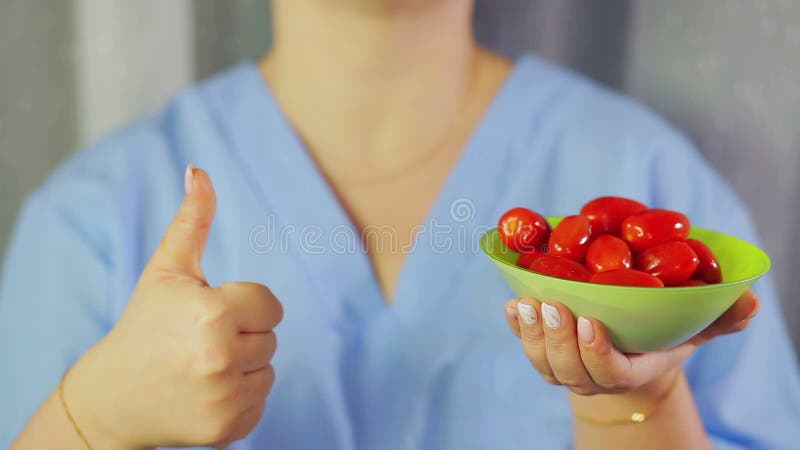 En los tomates de cereza de las manos de las mujeres La mano muestra la clase