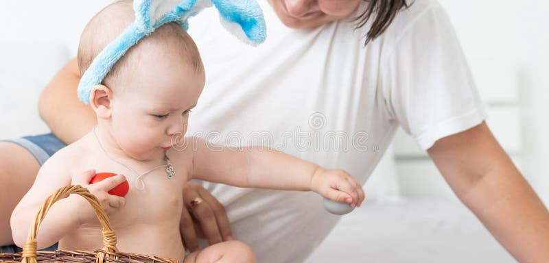 En lycklig familj som firar påskårens moder- och babyboöron hemma med färgstarka ägg royaltyfri fotografi