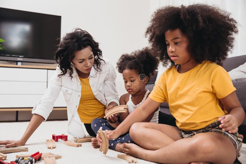 En mamma med två dotter spelar leksak i lägenheten. Barntillsyn - svart hemmabruk
