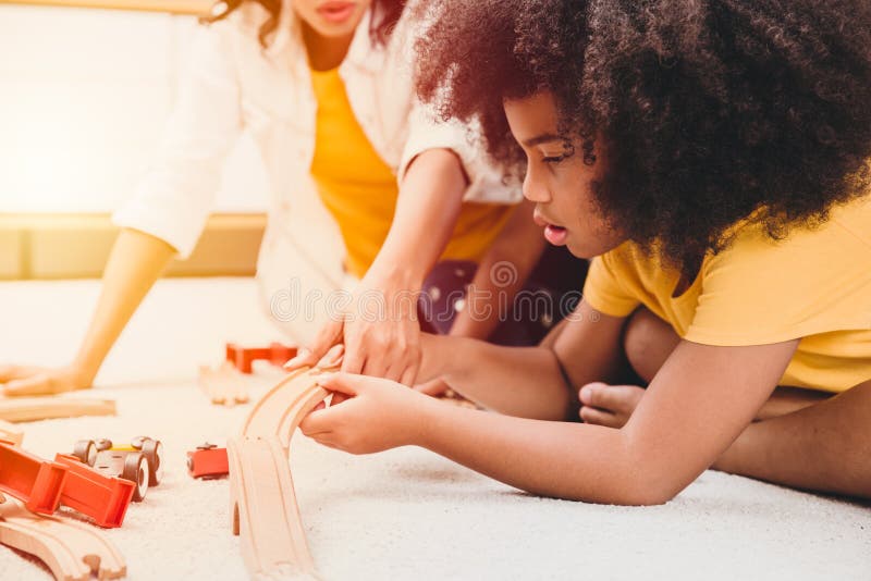 En mamma som bor med två dotters inlärning och leker puzzelleksak i hemlägenheten. barntillsyn och barnomsorg i vardagsrummet