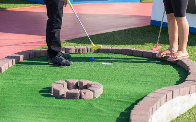 En man förbereder sig att slå en boll under den mini- golfleken arkivbilder En man förbereder sig att slå en boll under den mini- golfleken arkivbilder