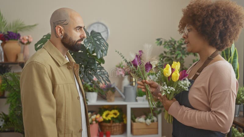 En man köper blommor från en kvinna som floriserar i en väldekorerad inomhusblomma arkivfoto