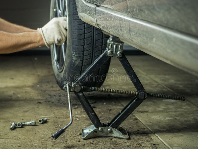 En man med handskar på att reparera det bakre hjulet av bilen arkivbild En man med handskar på att reparera det bakre hjulet av bilen arkivbild