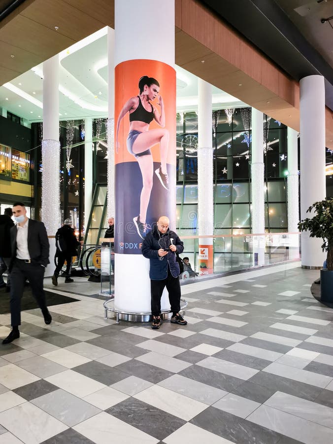 Moscow. Russia. February 3, 2022. A man in a shopping center uses a smartphone in front of an advertisement for sports equipment. Moscow. Russia. February 3, 2022. A man in a shopping center uses a smartphone in front of an advertisement for sports equipment.
