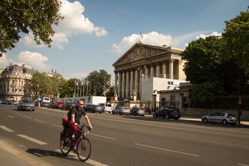 En man rider en cykel längs vägen längs medborgaren Assamley i Paris royaltyfria bilder En man rider en cykel längs vägen längs medborgaren Assamley i Paris royaltyfria bilder