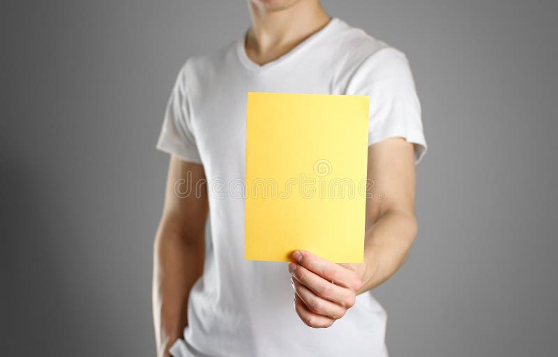 En man rymmer ett gult papper i hans hand Visar en tom reklamblad fotografering för bildbyråer En man rymmer ett gult papper i hans hand Visar en tom reklamblad fotografering för bildbyråer