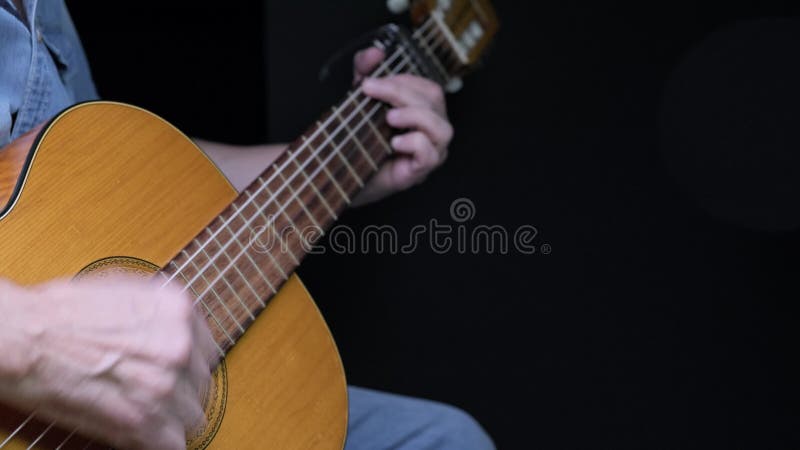 En man som leker på akustiska gitarrer på mörk bakgrund. tama hobbyer