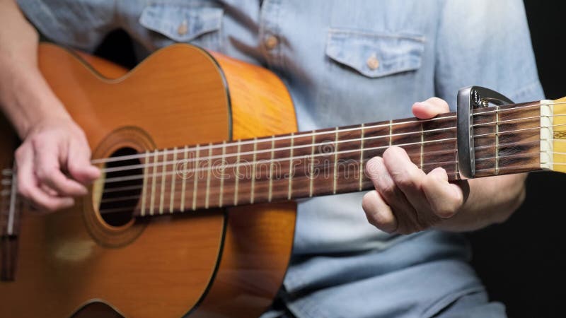 En man som leker på akustiska gitarrer på mörk bakgrund. tama hobbyer