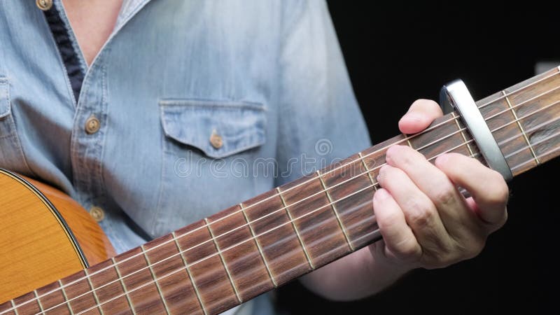 En man som leker på akustiska gitarrer på mörk bakgrund. tama hobbyer