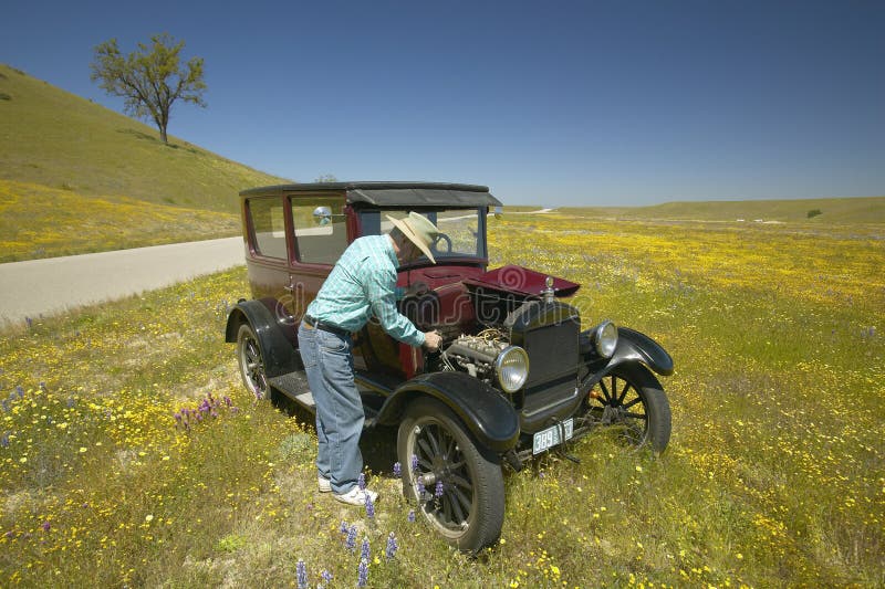 A man repairing his maroon Model T, surrounded by spring flowers off of Route 58, Shell Road, CA. A man repairing his maroon Model T, surrounded by spring flowers off of Route 58, Shell Road, CA