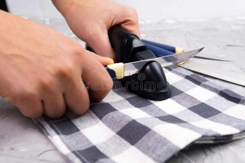 Sharpening a knife. Close-up of a man using a sharpener to sharpen a knife blade. Sharpening a knife. Close-up of a man using a sharpener to sharpen a knife blade