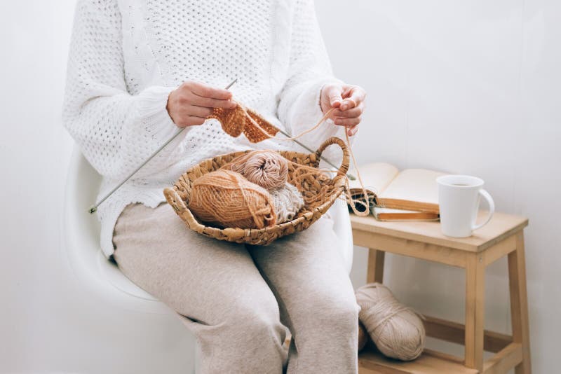 A middle-aged woman is engaged in home handicraft knitting, knitting with threads. Home activity hobby during quarantine or free time. Cozy knitting or small business concept. A middle-aged woman is engaged in home handicraft knitting, knitting with threads. Home activity hobby during quarantine or free time. Cozy knitting or small business concept