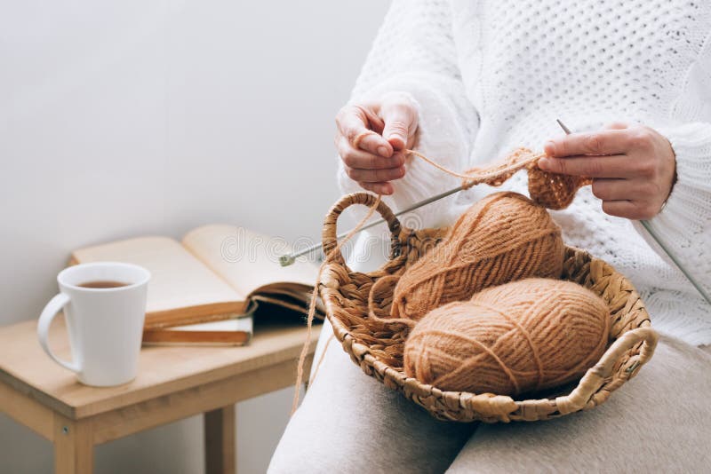 A middle-aged woman is engaged in home handicraft knitting, knitting with threads. Home activity hobby during quarantine or free time. Concept for an activity for the soul at home. A middle-aged woman is engaged in home handicraft knitting, knitting with threads. Home activity hobby during quarantine or free time. Concept for an activity for the soul at home