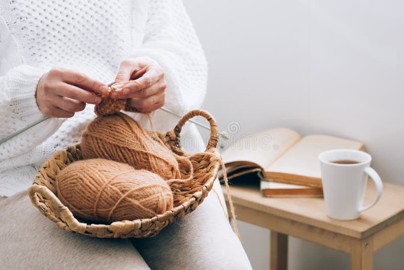 A middle-aged woman is engaged in home handicraft knitting, knitting with threads. Home activity hobby during quarantine or free time. Concept for an activity for the soul at home. A middle-aged woman is engaged in home handicraft knitting, knitting with threads. Home activity hobby during quarantine or free time. Concept for an activity for the soul at home