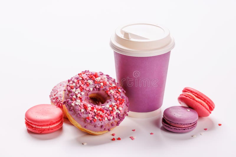 En munklig uppvisning av färgade makaronnötter och en kaffekopp av papper på vit bakgrund royaltyfria foton