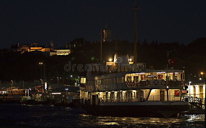 En offentlig färja som kallas ’Vapur ’på Eminonu port under den Topkapi slotten av ottomanvälden vid natt royaltyfria foton En offentlig färja som kallas ’Vapur ’på Eminonu port under den Topkapi slotten av ottomanvälden vid natt royaltyfria foton