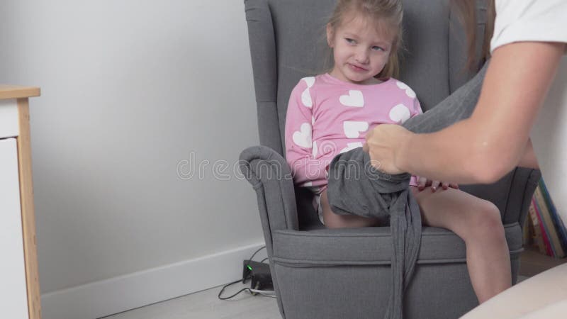 En omtänksam mamma sätter munkavle på sin lilla dotter hemma lager videofilmer