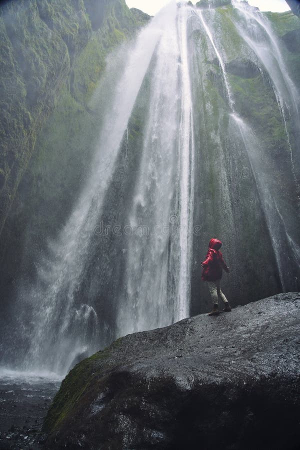 En personadmirnig skönheten av den Skogafoss vattenfallet som lokaliseras i Island royaltyfri foto En personadmirnig skönheten av den Skogafoss vattenfallet som lokaliseras i Island royaltyfri foto