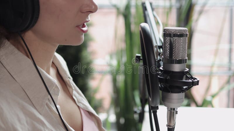 En poddsändningskvinna leder radioshow i mikrofonen i studio spbi
