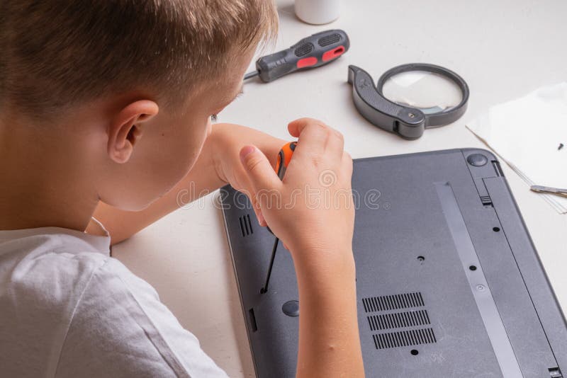 En pojke på 10 år sorterar en bärbar dator för rengöring och underhåll Selektivt fokus Screwdrivers, purge cylinder, förstoring arkivbild