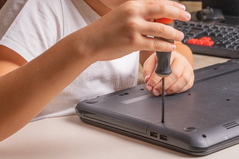 En pojke på 10 år sorterar en bärbar dator för rengöring och underhåll Selektivt fokus Screwdrivers, purge cylinder, förstoring arkivfoton