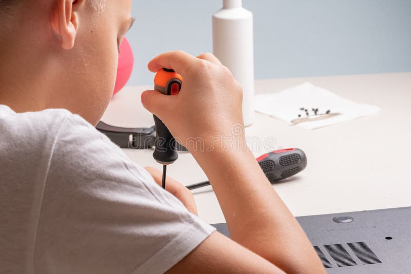 En pojke på 10 år sorterar en bärbar dator för rengöring och underhåll Selektivt fokus Screwdrivers, purge cylinder, förstoring royaltyfri fotografi
