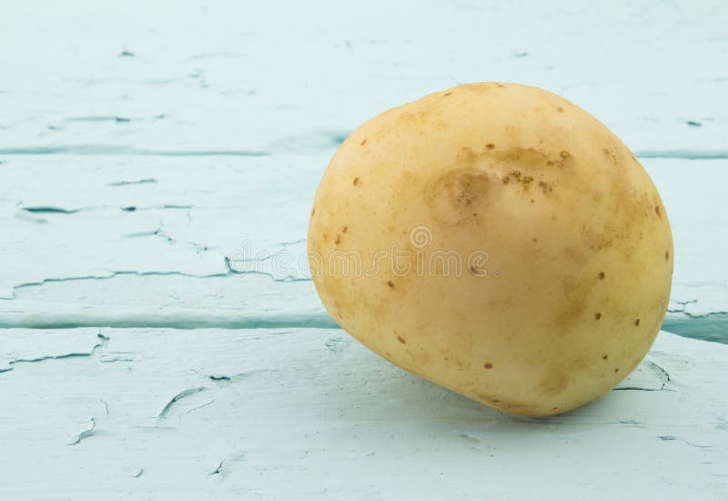 En potatis på målat trä för havsgräsplan arkivfoton En potatis på målat trä för havsgräsplan arkivfoton